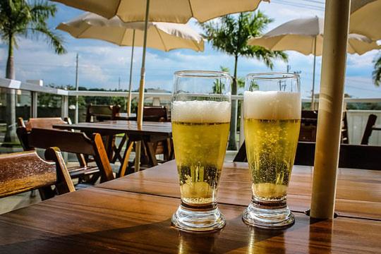 雅瓜里乌纳Hotel Portal das Águas的木桌旁放两杯啤酒