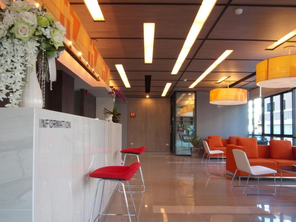 南邦ABIZZ Hotel Lampang Airport的大厅,大楼内摆放着橙色椅子和桌子