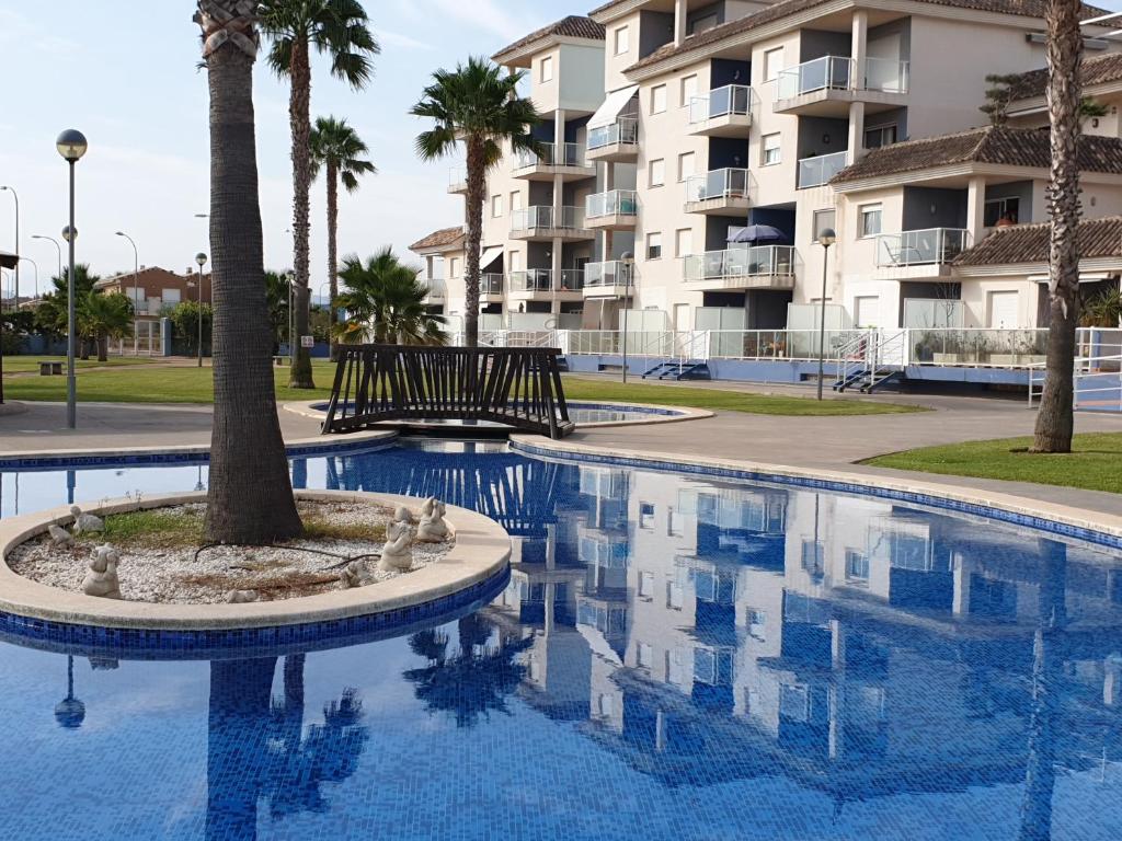 埃尔韦尔赫尔AguaBlanca 1km playa Deveses的一座建筑前的游泳池,里面种着棕榈树