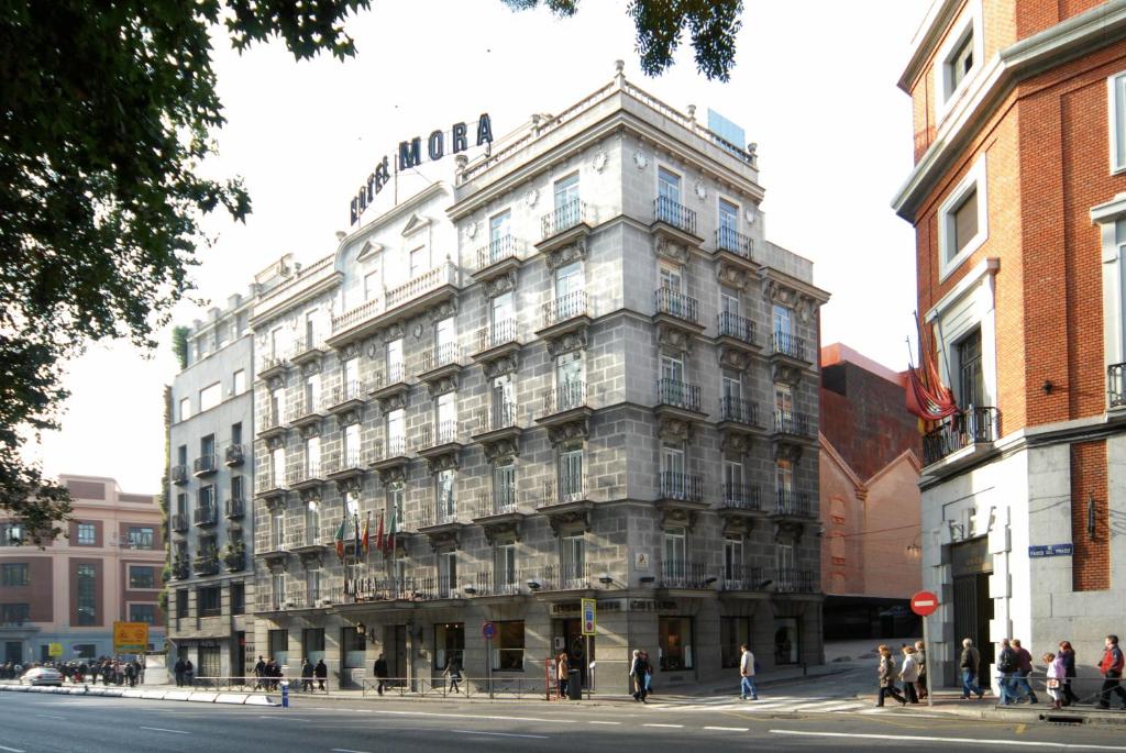 马德里Hotel Mora by MIJ的一条城市街道上高大的建筑,人们站在街道周围