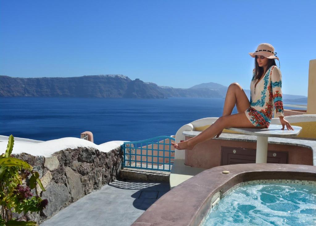 伊亚圣托里尼岛天堂宅酒店的坐在游泳池旁桌子上的女人