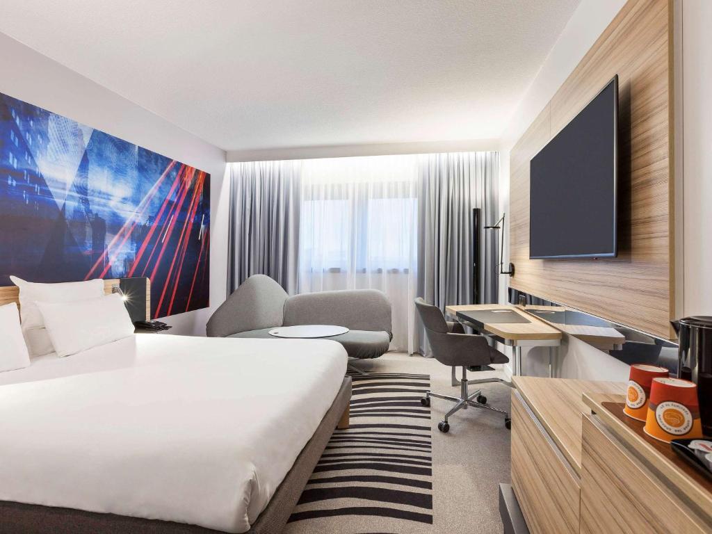 图尔诺富特旅游中心火车站酒店的酒店客房设有一张床、一张书桌和一台电视机。