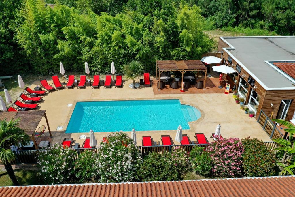 翁德尔The Originals City, Hôtel Le Lodge, Bayonne Nord的享有带红色椅子的游泳池和房屋的空中景致