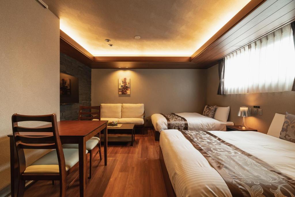 别府GRAND BASE Beppu的酒店客房设有两张床、一张桌子和一张桌子。