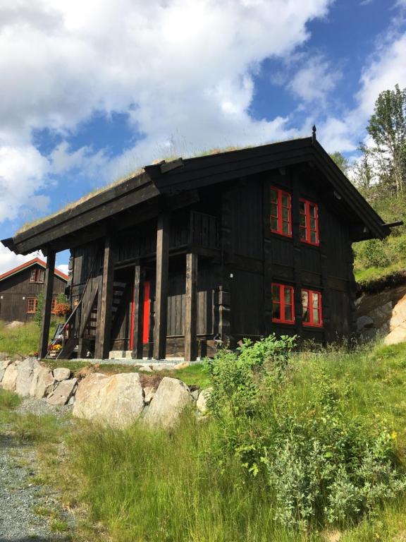 KyrkjemoenNilsrud 30 Feriehus的山上的黑色房子,有红色的窗户