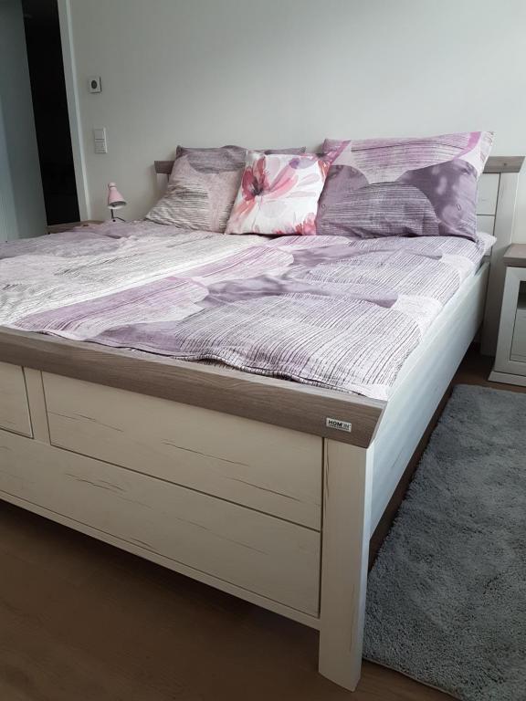 维也纳Vienna Home48的一张木架床和一张带床垫罩的白色床