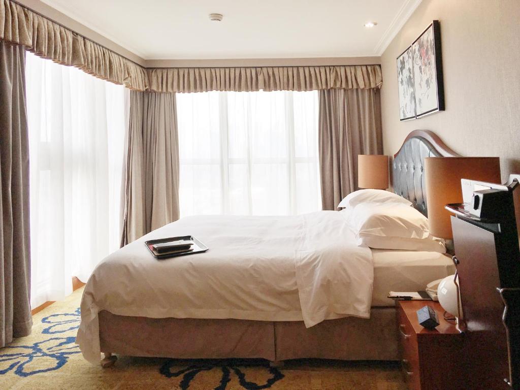 武汉武汉天禄华美达广场酒店的一间卧室设有一张大床和一个大窗户