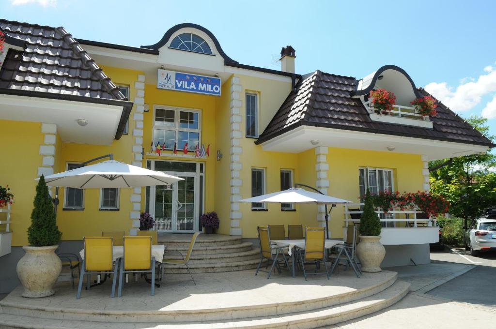 大格拉迪什泰Sobe Milo的一座黄色的建筑,配有桌椅和遮阳伞