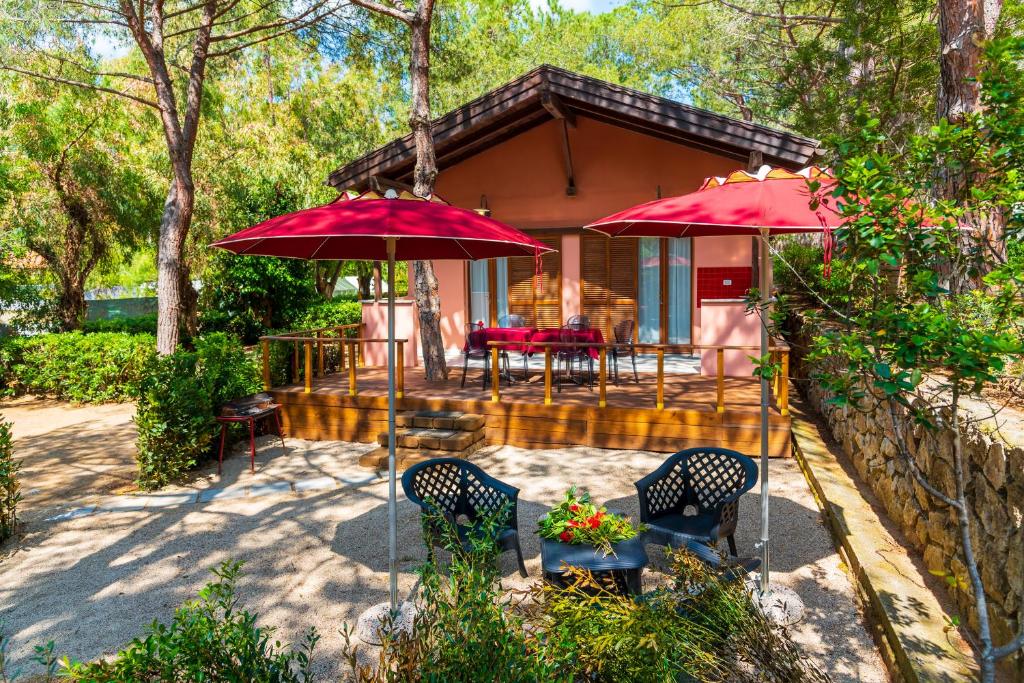 卡波利韦里Camping Lacona Pineta的一座房子,配有两把红色遮阳伞和一个庭院