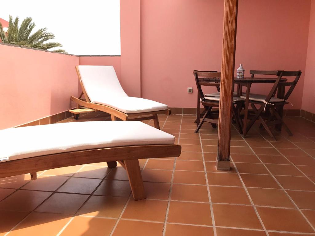 大塔拉哈尔Ático Sun&Beach的一间设有桌椅的客房,并铺有地板