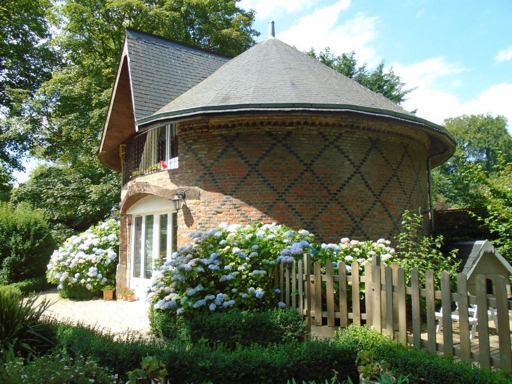 BracquetuitLE GITE DU COLOMBIER的一座砖砌的小建筑,有栅栏和鲜花