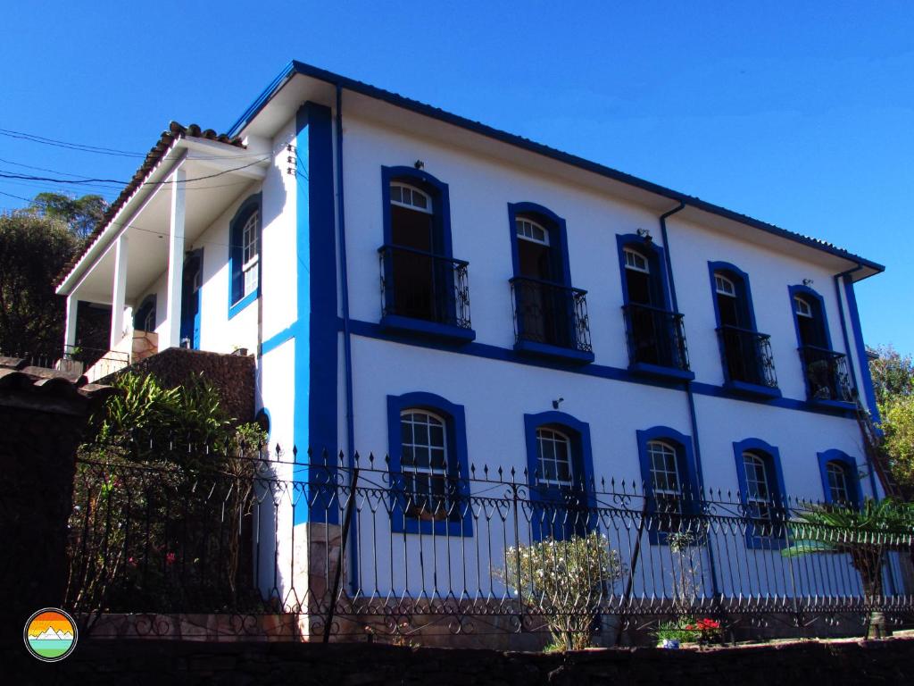 欧鲁普雷图Buena Vista Hostel的白色的房子,设有黑窗和栅栏