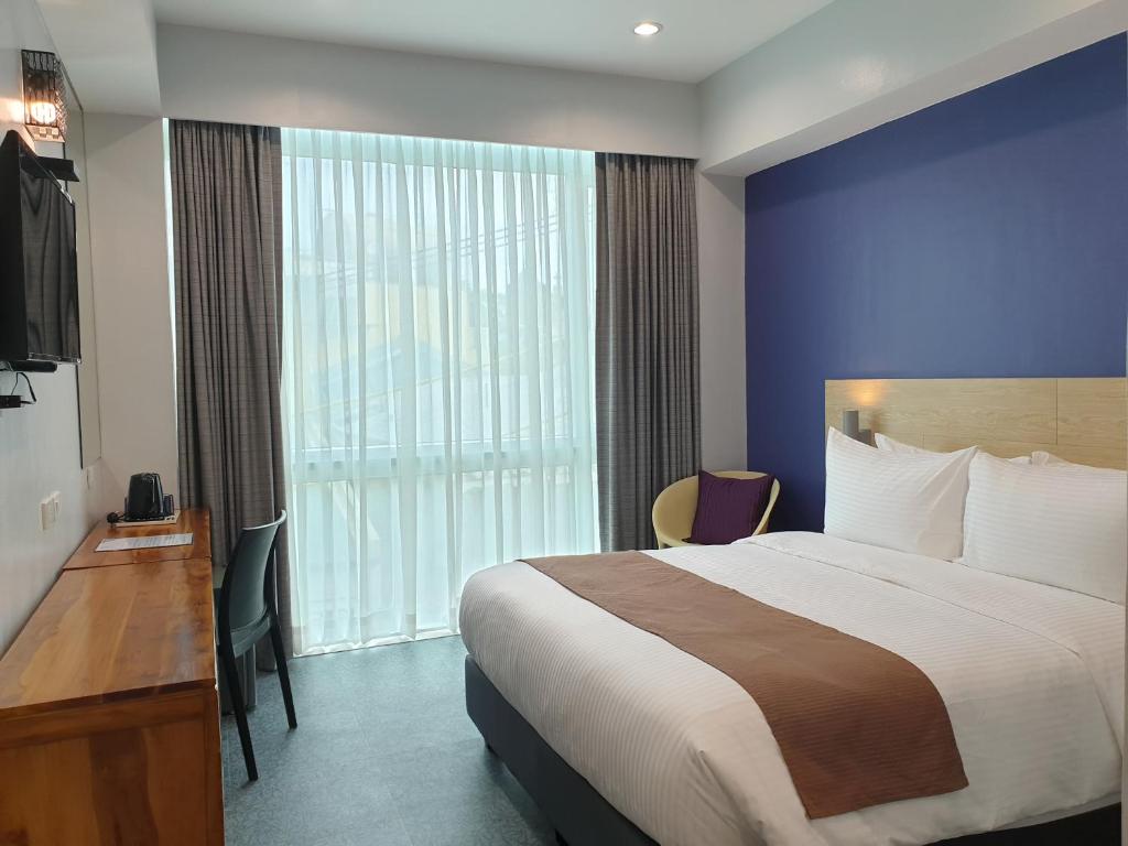 马尼拉Leez Inn Makati的酒店客房设有一张床和一个大窗户
