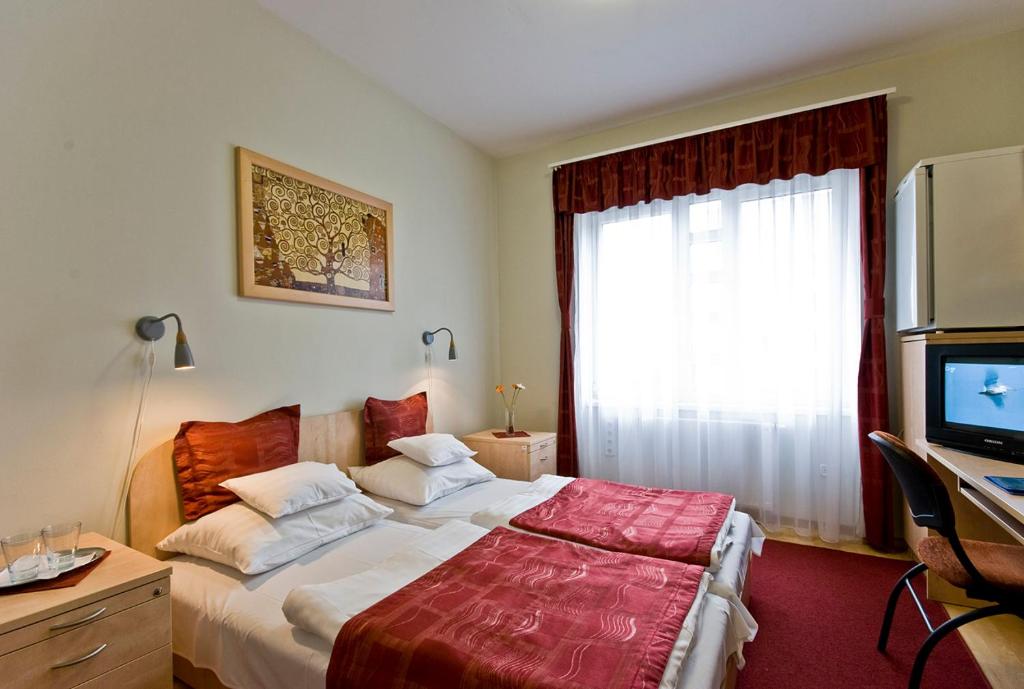多瑙新城格贝莉酒店 的一间卧室配有一张床、一张书桌和一台电视