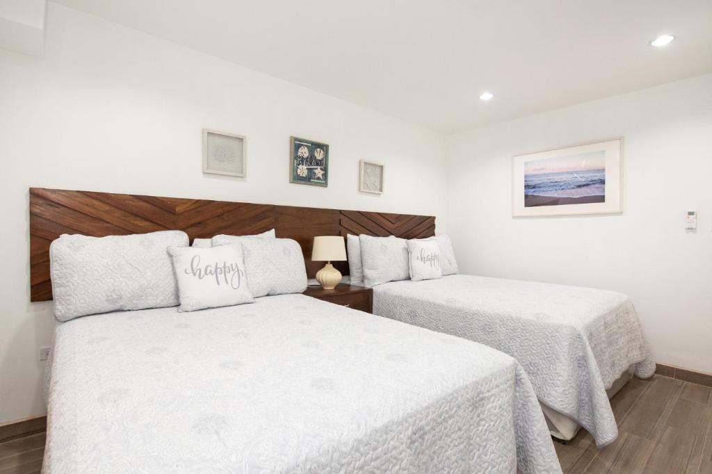 圣佩德罗La Casa de Paz Hotel的一间卧室配有两张带白色床单的床
