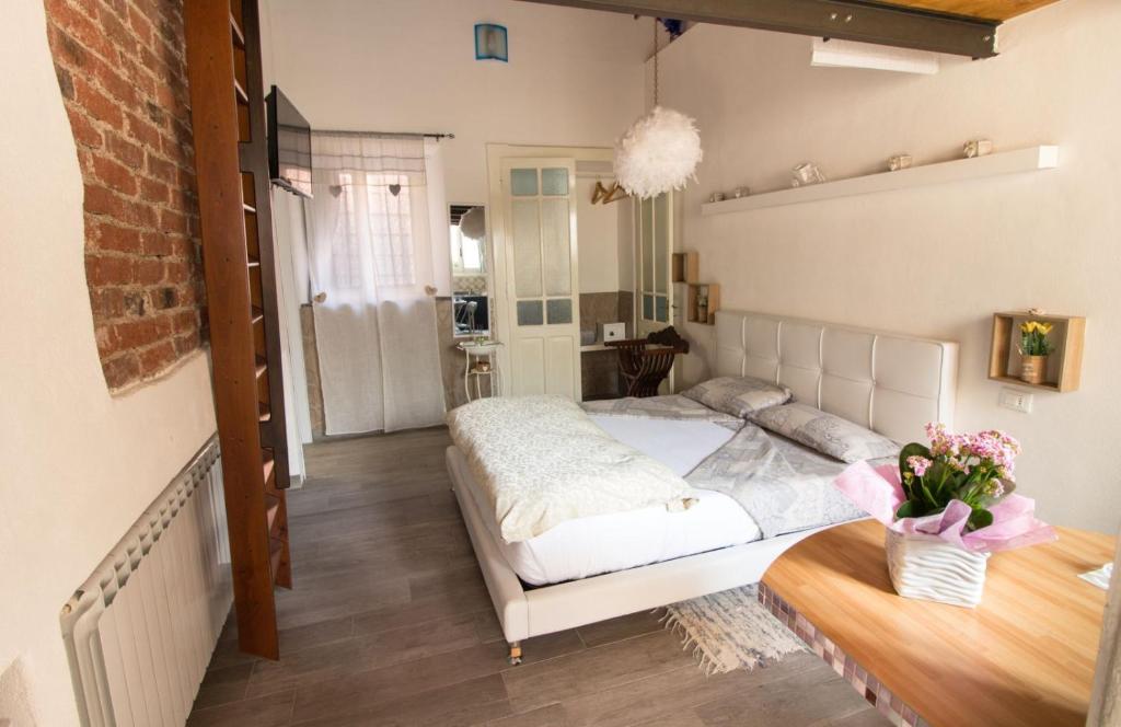 博尔戈马内罗Mansarde & Suite Maison 1706 Lago Orta的一间卧室配有一张床和一张鲜花桌