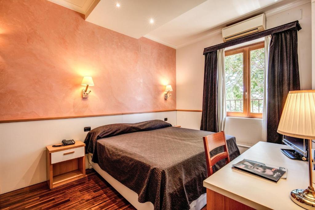罗马罗马提布提纳地铁酒店的配有一张床、一张书桌和一扇窗户的酒店客房