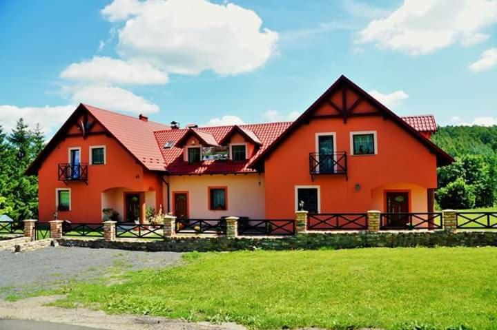 MirskWydrza-Przystań的一座大型橙色房子,在田野上设有围栏