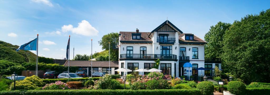 滨海韦克Boutique hotel Puur Zee - Adults Only的一座白色的大房子,前面设有一个花园