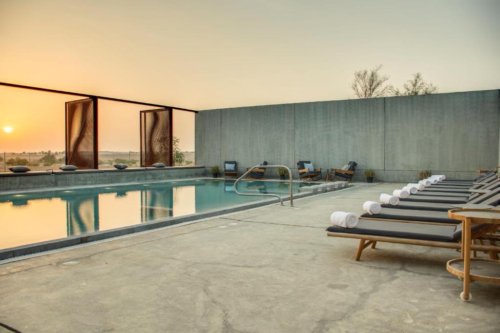 沙迦Al Faya Retreat by Sharjah Collection的游泳池旁设有一排躺椅