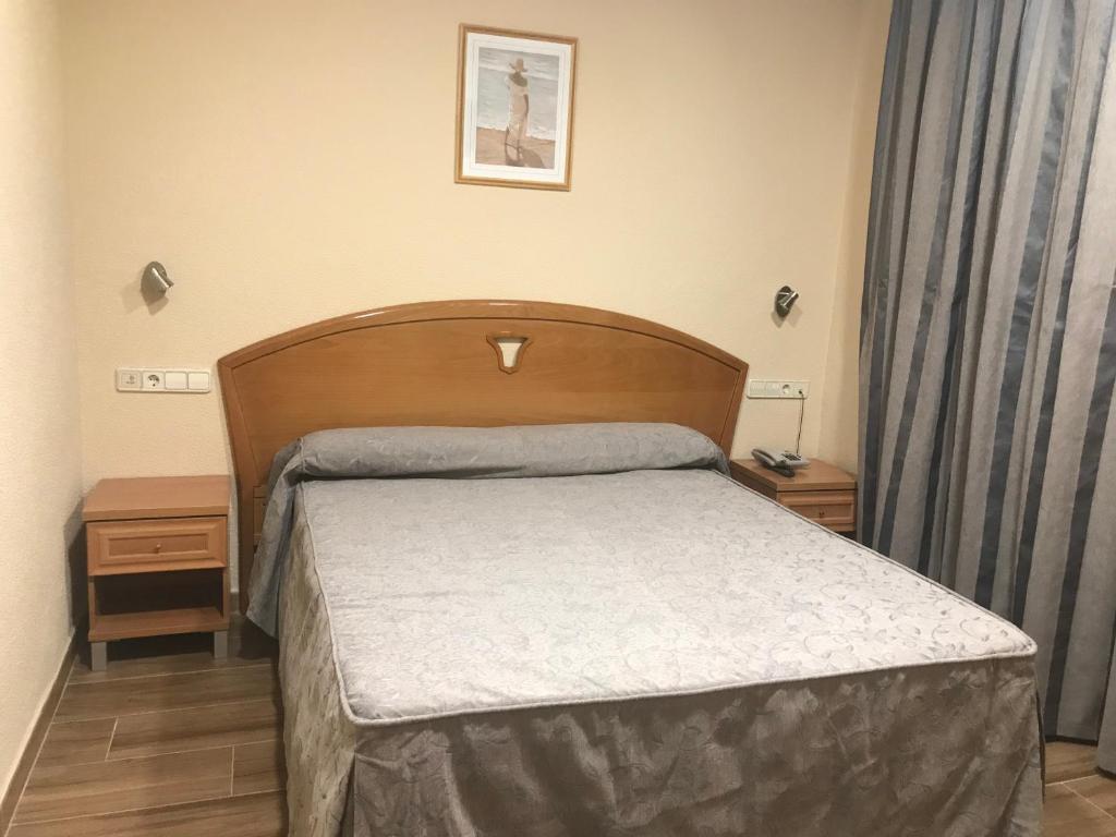 乌马内斯-德马德里拉乌尼翁酒店的一间卧室配有一张带木制床头板的床