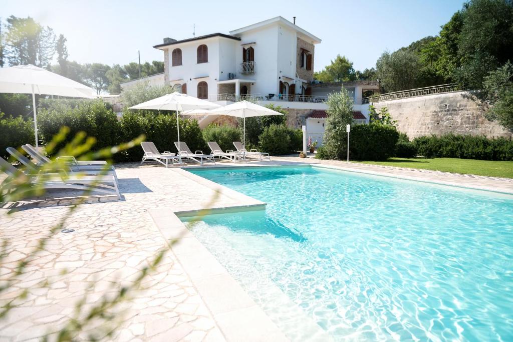曼杜里亚Tenuta Cardinale的一个带椅子的游泳池和一个背景房子