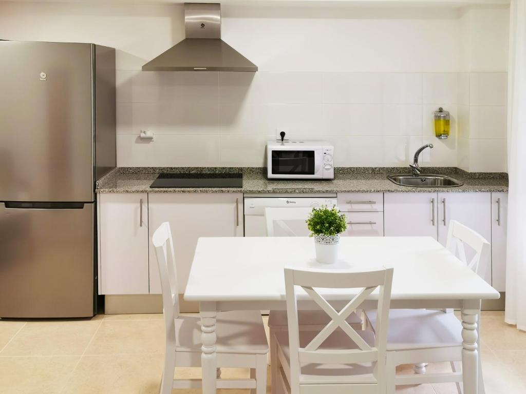 比韦罗Duerming Family Viveiro 3 Rooms的厨房配有白色的桌椅和冰箱。