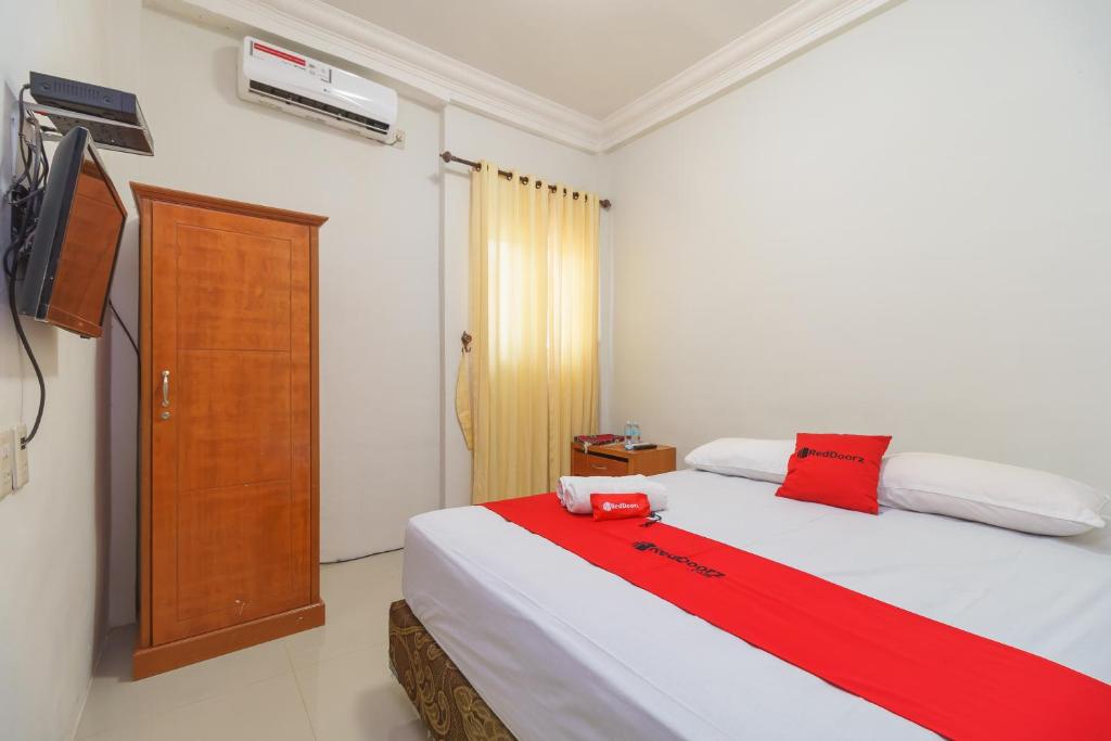 班达亚齐RedDoorz Syariah @ Panglima Nyak Makam Aceh的卧室配有红色色调的大型白色床