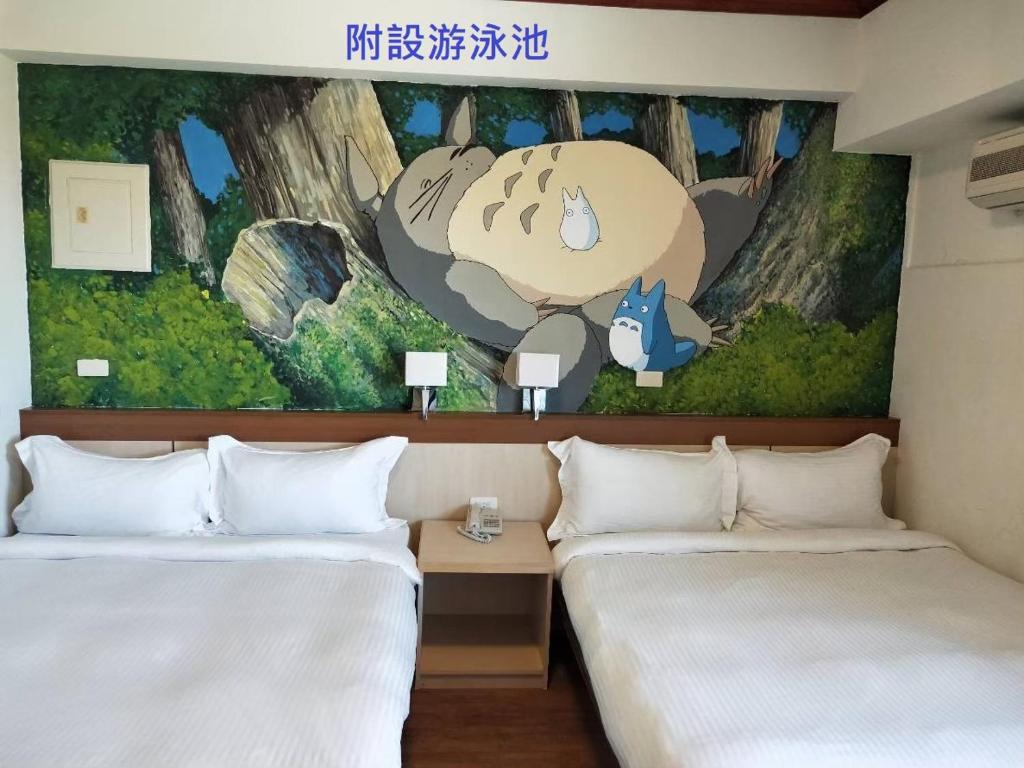 恒春古城垦丁小天地度假旅店的两张位于酒店客房的床铺,配有壁画