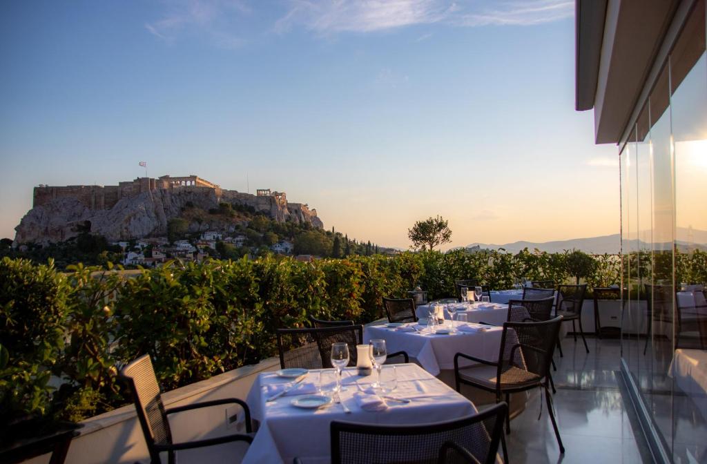 雅典雅典伊莱克特拉宫的餐厅设有桌椅,位于山丘的背景中
