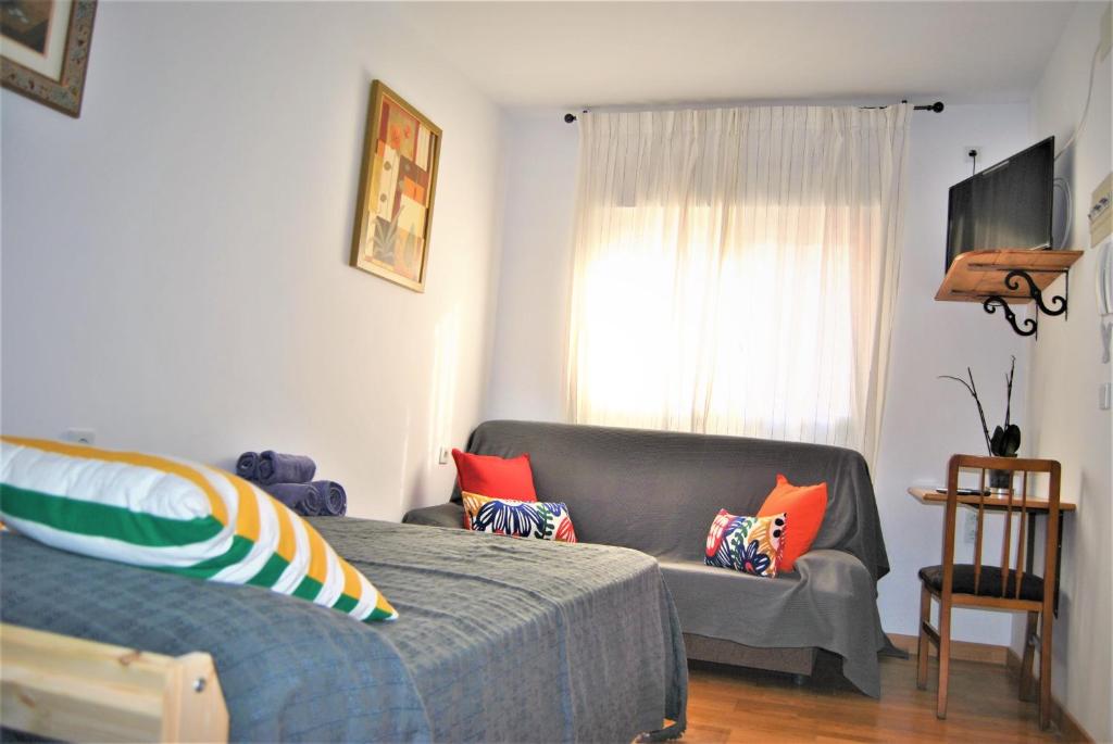 马拉加KHORS的一间卧室配有一张床、一张沙发和一个窗口