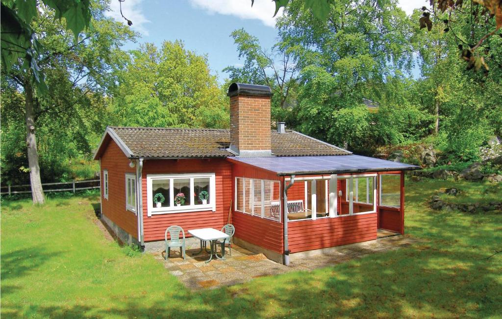 龙讷比Nice Home In Ronneby With Ethernet Internet的一座小红色房子,在院子里配有桌椅