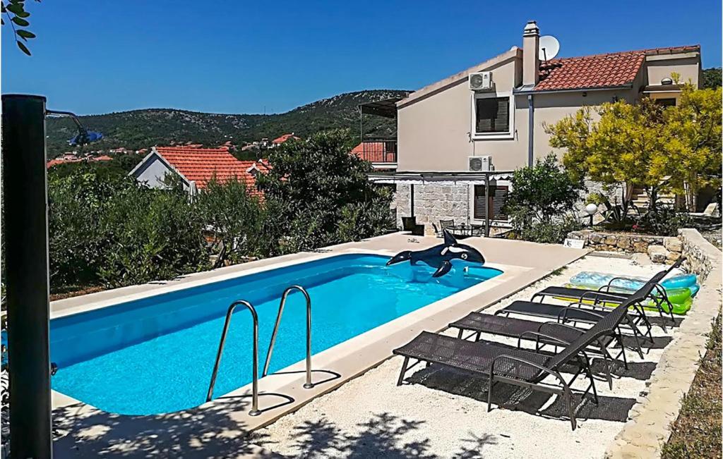 维尼斯切Awesome Home In Vinisce With Outdoor Swimming Pool的一个带两把椅子的游泳池以及一座房子