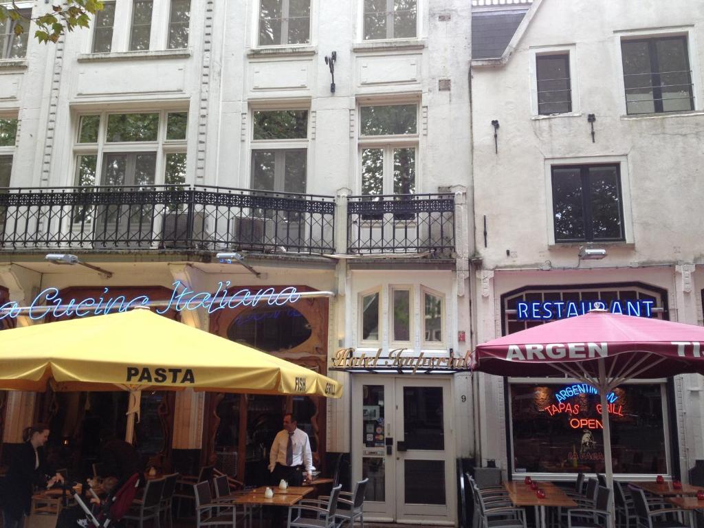 阿姆斯特丹帝国酒店的建筑前有桌子和遮阳伞的街道