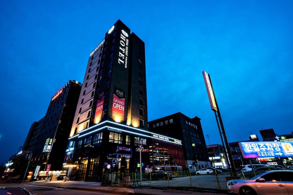始兴市Siheung Seoul Tourist Hotel的一座高大的建筑,旁边是 ⁇ 虹灯标志