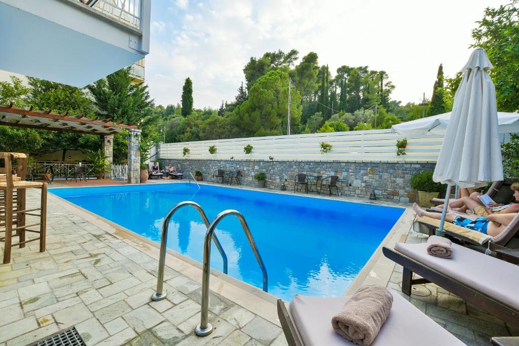 奥林匹亚奈达酒店的一座游泳池,里面摆放着椅子和遮阳伞,可供两人使用