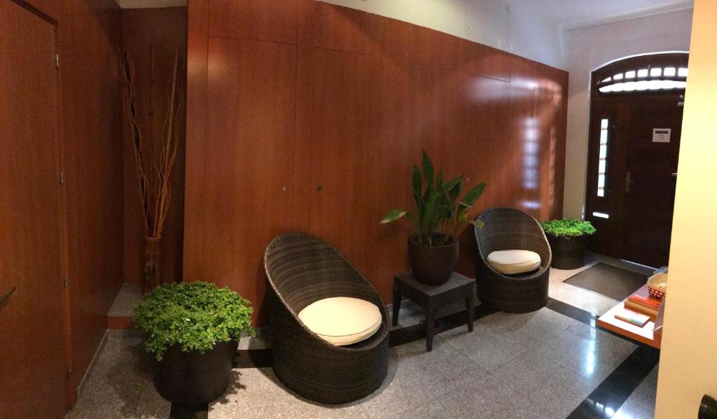 锡切斯塞特格斯公寓酒店的大堂设有三把椅子和盆栽植物