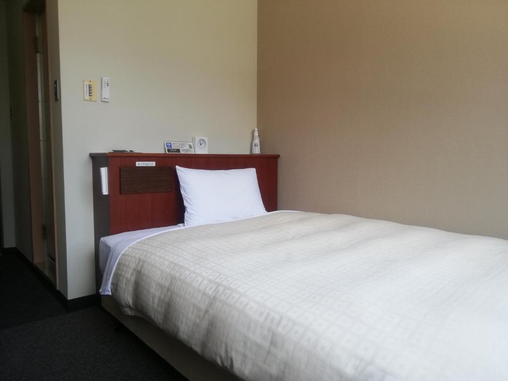 周南市Hotel Tokuyama Hills Heiwadoriten的一间卧室配有一张大床和白色床单