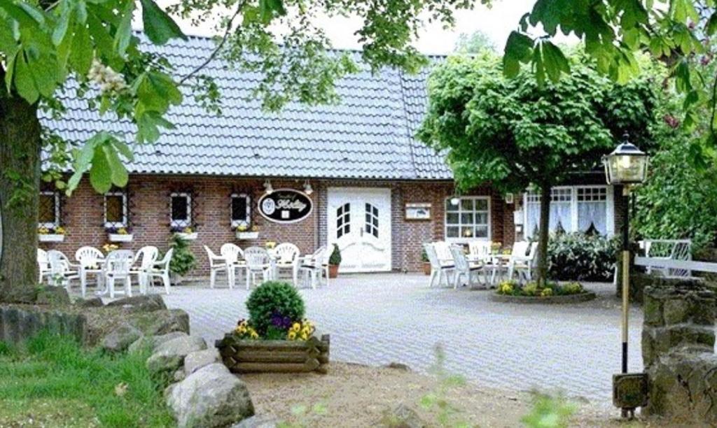HavekostGästehaus Höltig的前面有白色椅子的砖房