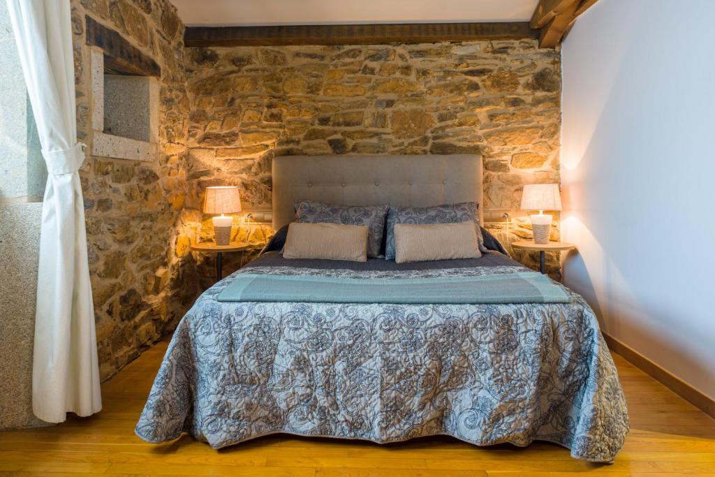 拉瓦克拉阿曼西奥酒店的石墙卧室配有1张床和2盏灯。