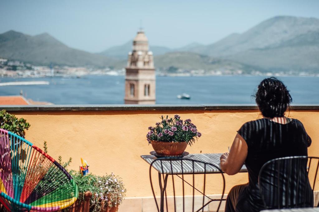 加埃塔米勒夸特罗森托住宿加早餐旅馆的坐在阳台上的女人,看着水