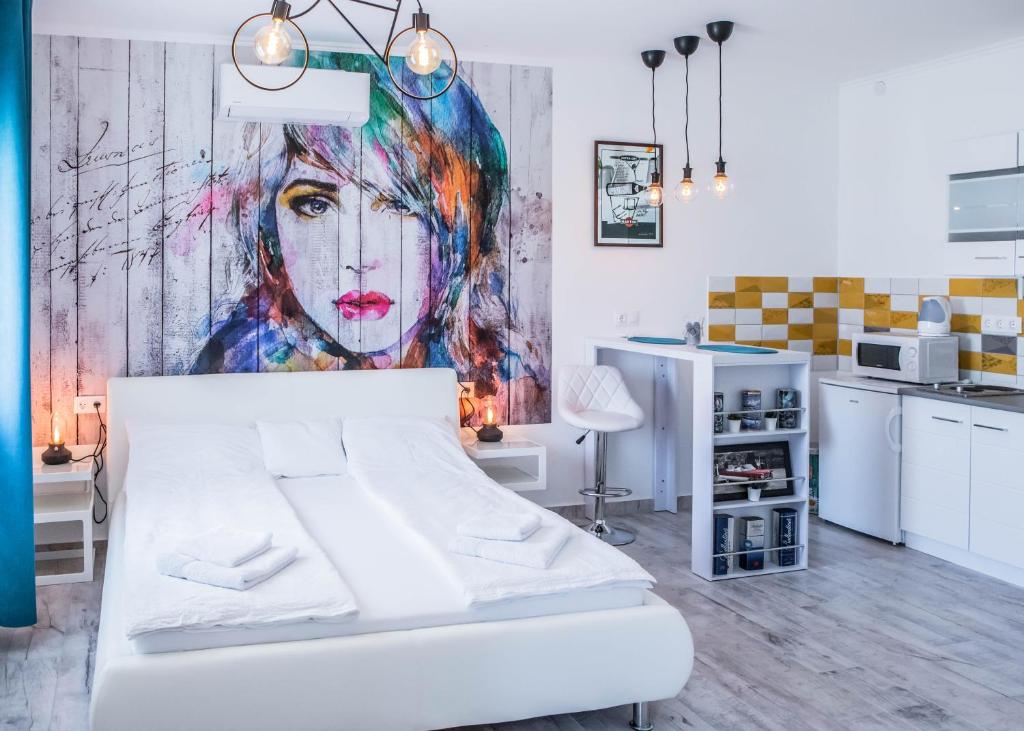 毛科Jázmin Apartman的卧室配有白色的床和墙上的绘画作品