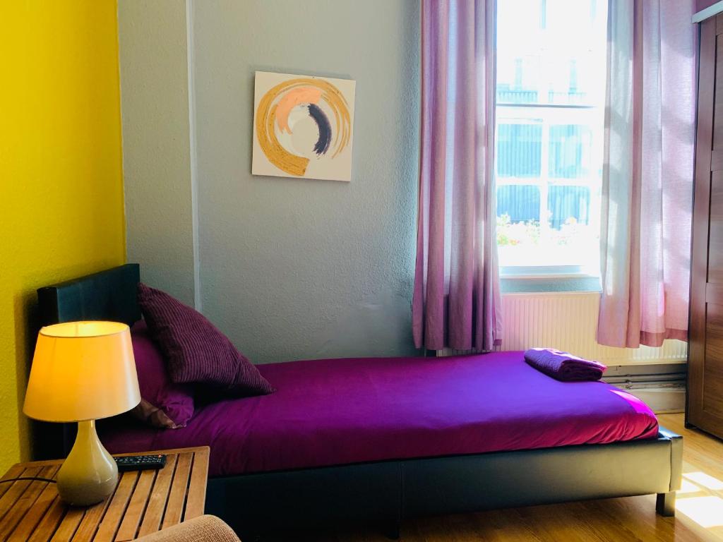 伦敦亚瑟王子酒店的一间卧室配有一张紫色床和窗户