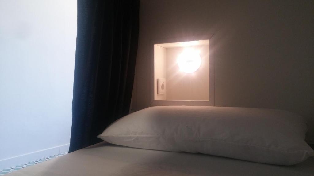 维戈R4Hostel的一间卧室配有一张带窗户灯的床