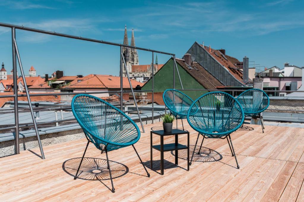 雷根斯堡威登霍夫酒店的屋顶上摆放着三把椅子和一张桌子