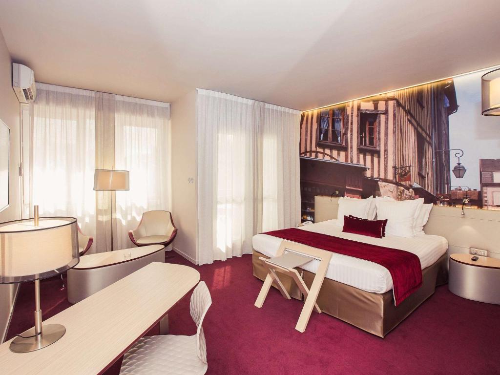 里摩日Mercure Limoges Centre的酒店客房带一张大床以及桌椅