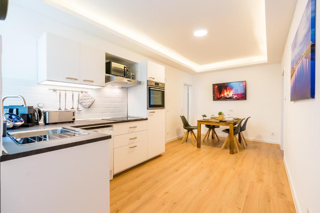 杜塞尔多夫马琳街中心公寓的厨房配有白色橱柜和桌椅