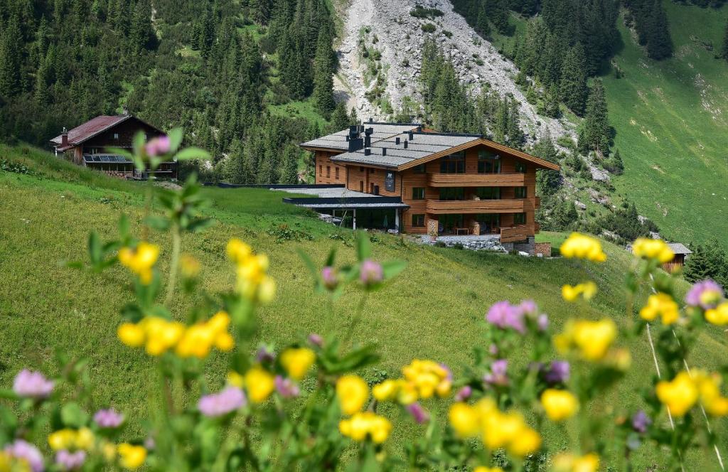 沃瑟姆阿尔伯格LUX ALP CHALET am Arlberg的山丘上,前方有鲜花的房子