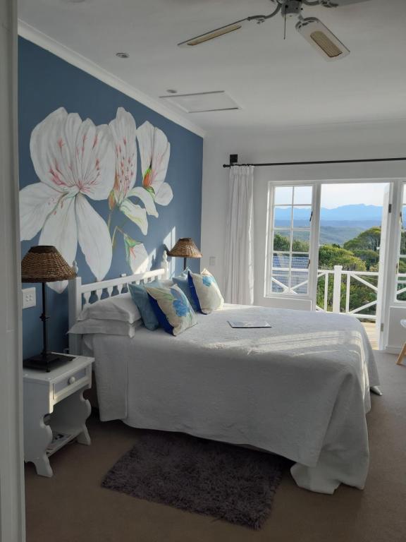 普利登堡湾弗拉马雷尔住宿加早餐旅馆的卧室配有白色的床铺和花卉壁画