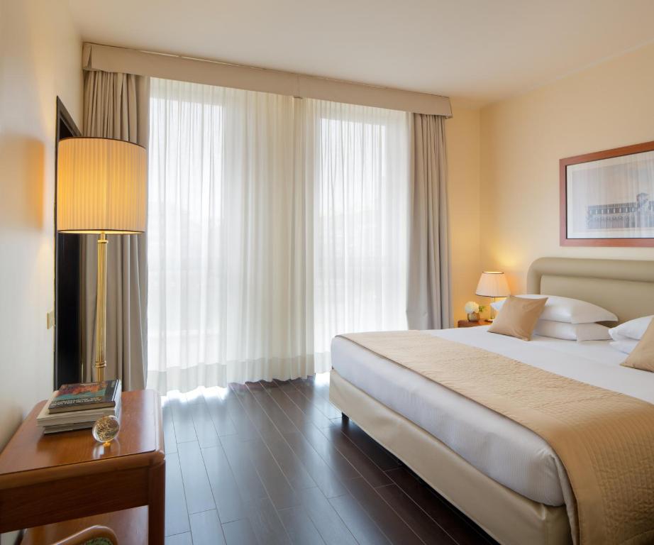 米兰星际商务宫殿酒店的酒店客房配有一张床和一张带台灯的桌子